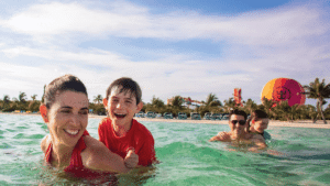 A family enjoys swimming in the ocean near a vibrant water park, showcasing a fun-filled day at the beach.